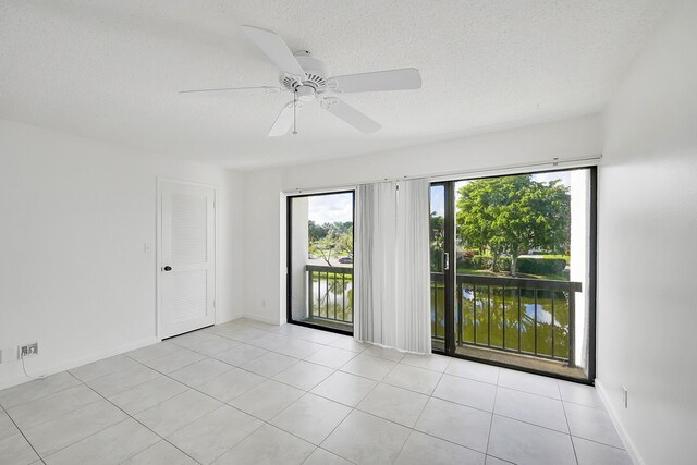 empty room with ceiling fan, light tile patterned floors, and a textured ceiling