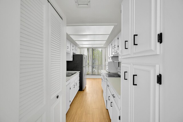 kitchen with white cabinets, electric range, stainless steel fridge, and light hardwood / wood-style floors