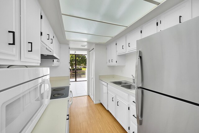 kitchen with dishwasher, white cabinetry, sink, stainless steel fridge, and light wood-type flooring