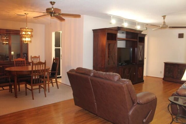 living room featuring ceiling fan with notable chandelier and wood-type flooring