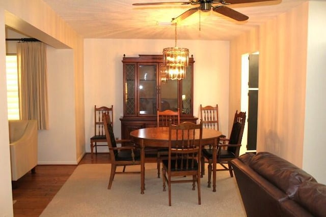 dining area with dark hardwood / wood-style flooring and ceiling fan with notable chandelier