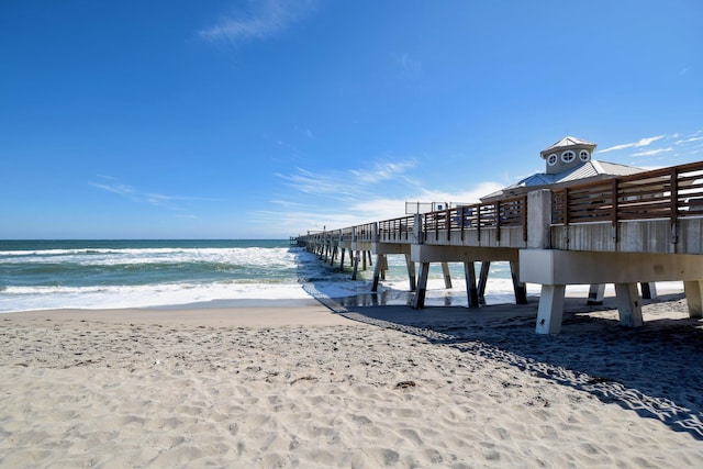 view of dock with a pier, a beach view, and a water view