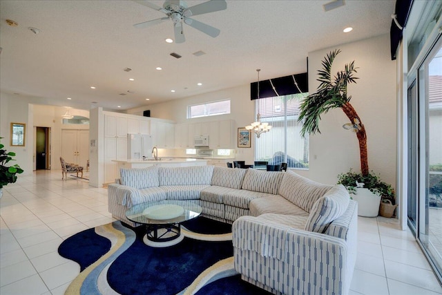 tiled living room featuring ceiling fan with notable chandelier and sink