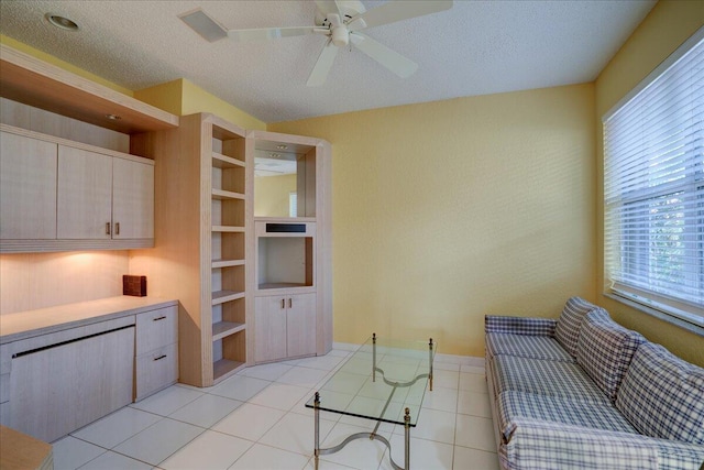 tiled living room with built in shelves, ceiling fan, and a textured ceiling