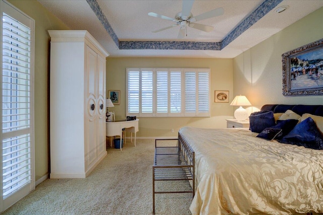 bedroom with ceiling fan, light colored carpet, a raised ceiling, and a textured ceiling