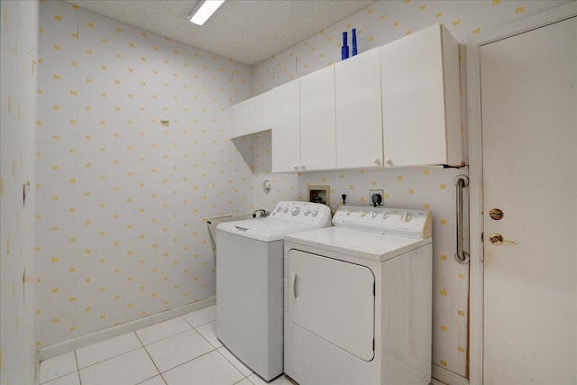 washroom with cabinets, separate washer and dryer, light tile patterned floors, and a textured ceiling