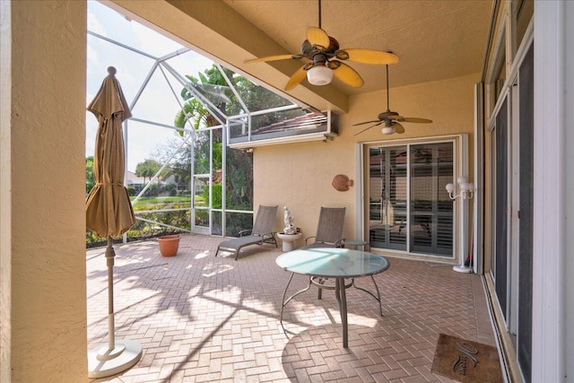 view of patio featuring ceiling fan and glass enclosure