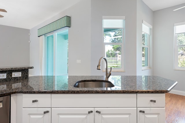 kitchen with sink, white cabinetry, a wealth of natural light, and dark stone counters