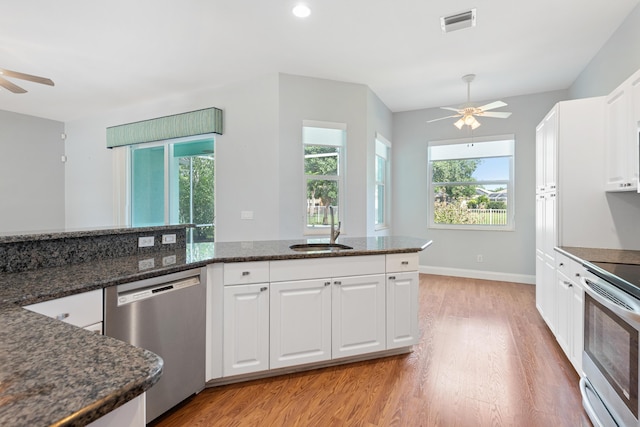 kitchen with white cabinets, appliances with stainless steel finishes, sink, and dark stone countertops