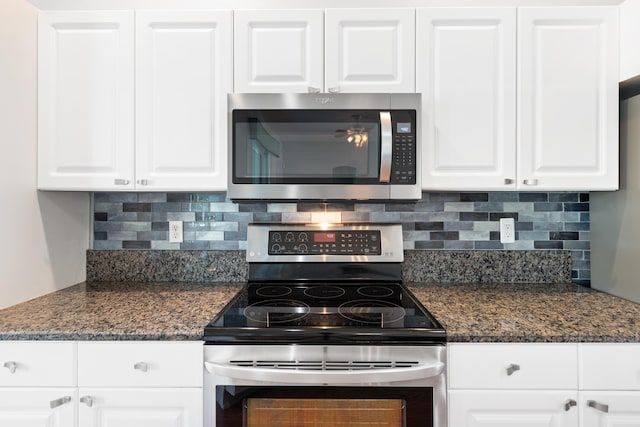 kitchen with decorative backsplash, white cabinetry, stainless steel appliances, and dark stone counters