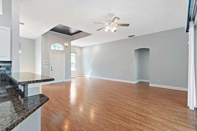 unfurnished living room featuring ceiling fan and hardwood / wood-style flooring