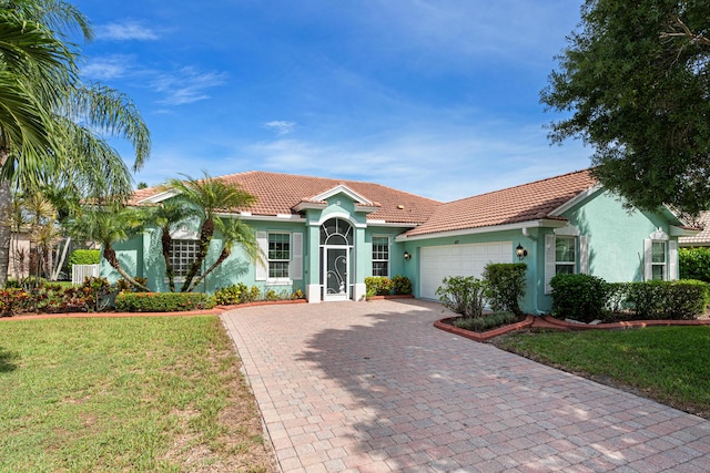 mediterranean / spanish home featuring a front lawn and a garage