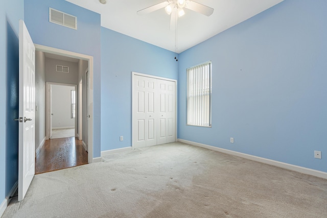 unfurnished bedroom featuring ceiling fan, light colored carpet, and a closet