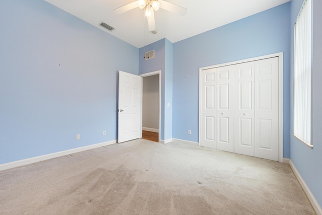 unfurnished bedroom featuring ceiling fan, a closet, and light carpet