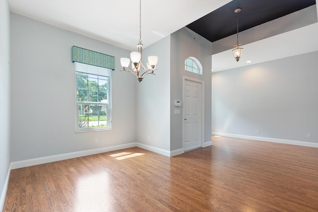 unfurnished room with hardwood / wood-style flooring and a notable chandelier