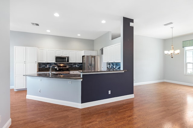 kitchen featuring white cabinetry, stainless steel appliances, backsplash, a chandelier, and hardwood / wood-style flooring