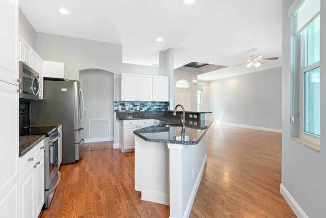 kitchen featuring white cabinets, appliances with stainless steel finishes, decorative backsplash, sink, and ceiling fan