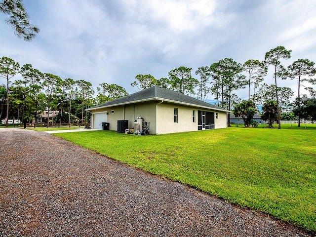 view of side of property with a garage, a yard, and central AC unit