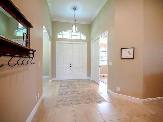 tiled foyer with ornamental molding and a high ceiling