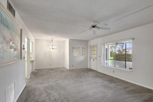 carpeted spare room featuring ceiling fan with notable chandelier and a textured ceiling