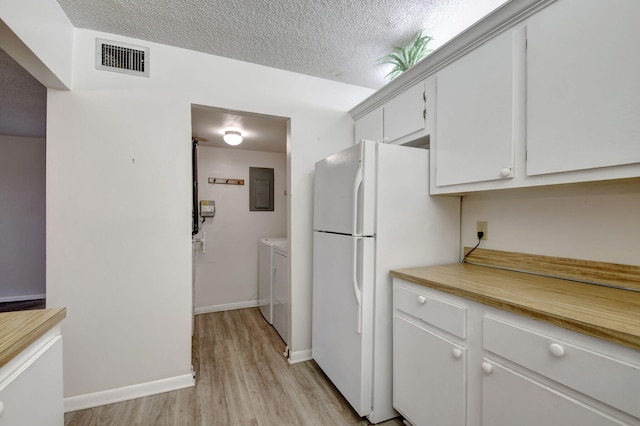 kitchen featuring a textured ceiling, washing machine and dryer, white cabinetry, white fridge, and electric panel