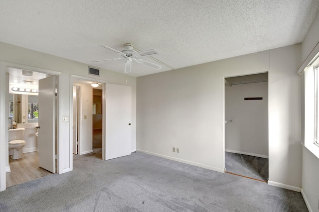 unfurnished bedroom featuring ensuite bathroom, ceiling fan, a textured ceiling, light carpet, and a closet