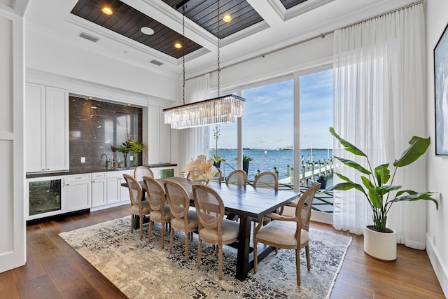 dining space with dark wood-type flooring, beam ceiling, a water view, coffered ceiling, and ornamental molding