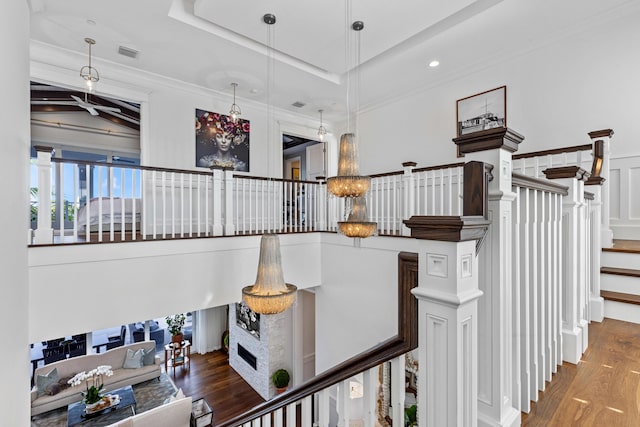 stairway with hardwood / wood-style flooring, ornamental molding, and a fireplace