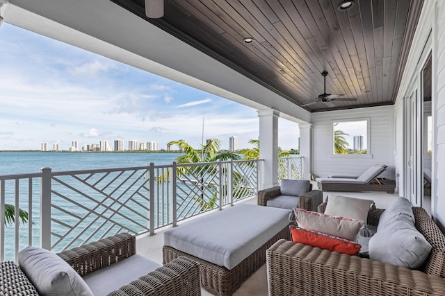 balcony with a water view, ceiling fan, and an outdoor living space