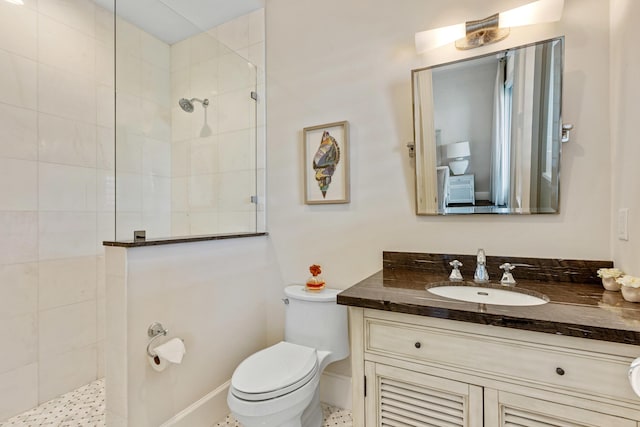 bathroom with vanity, toilet, and a tile shower