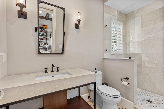 bathroom featuring tiled shower, toilet, and sink