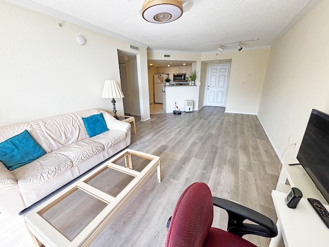 living room with crown molding, light wood-type flooring, and a textured ceiling