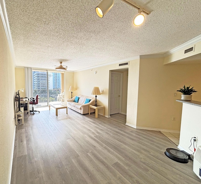 living room with hardwood / wood-style flooring, a textured ceiling, a wall of windows, and ornamental molding