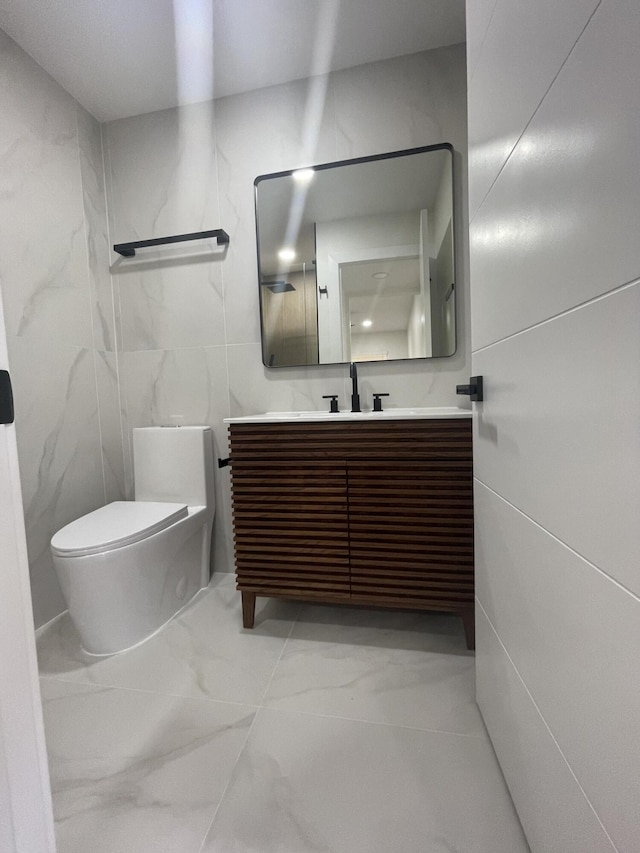 bathroom with toilet, vanity, and tile walls