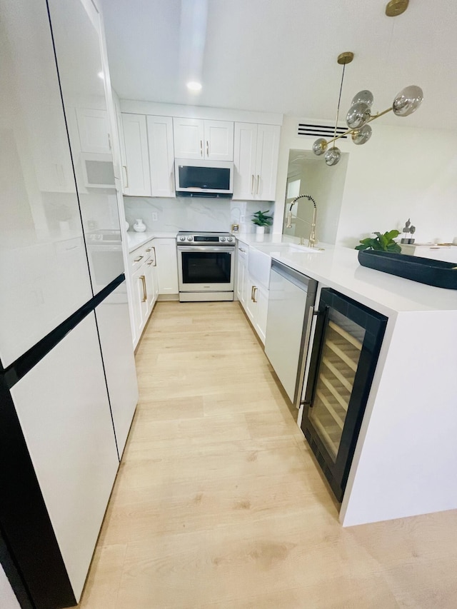 kitchen featuring stainless steel range with electric cooktop, decorative backsplash, wine cooler, white cabinets, and sink