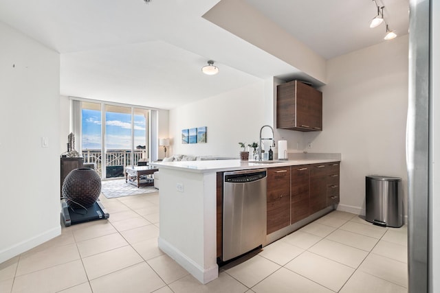 kitchen with stainless steel dishwasher, sink, light tile patterned floors, expansive windows, and dark brown cabinets