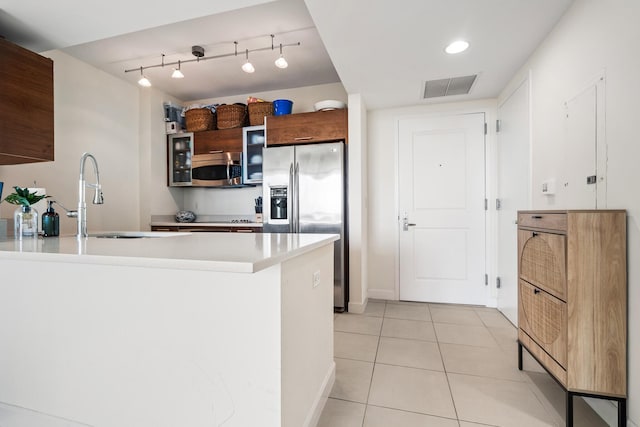 kitchen with light tile patterned floors, sink, appliances with stainless steel finishes, and kitchen peninsula