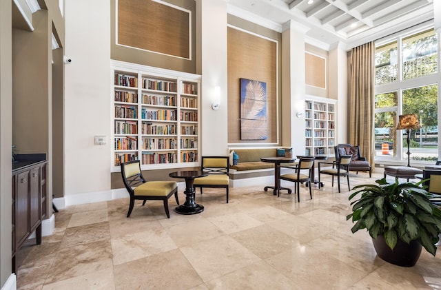 living area featuring a towering ceiling, coffered ceiling, and beamed ceiling