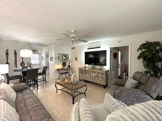 living room with ceiling fan, a textured ceiling, and light tile patterned floors