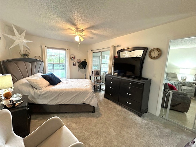 carpeted bedroom with ceiling fan, access to exterior, and a textured ceiling