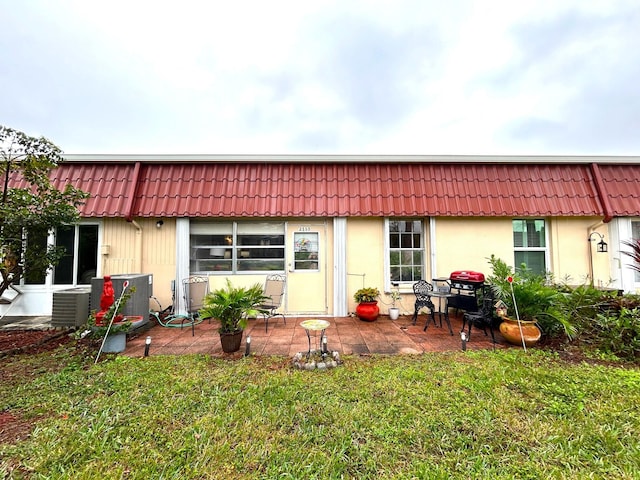 rear view of property with central AC unit, a lawn, and a patio