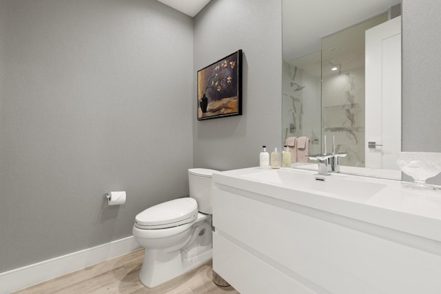 bathroom with vanity, tiled shower, hardwood / wood-style floors, and toilet