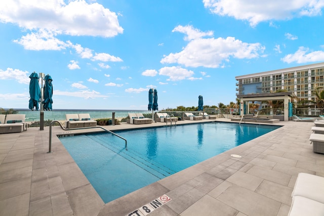 view of pool with a patio area and a water view