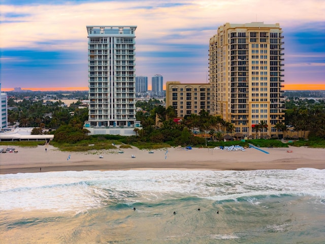 outdoor building at dusk featuring a water view and a beach view