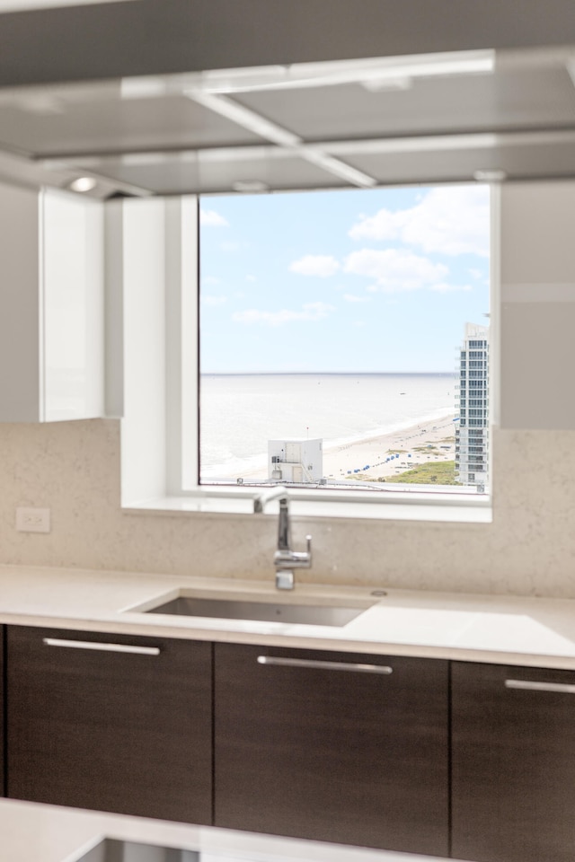 kitchen featuring dark brown cabinetry, sink, and a water view