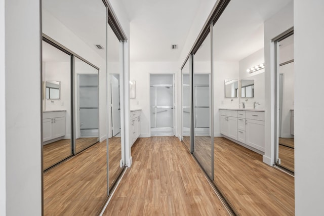 unfurnished bedroom featuring ensuite bath, light hardwood / wood-style floors, and two closets