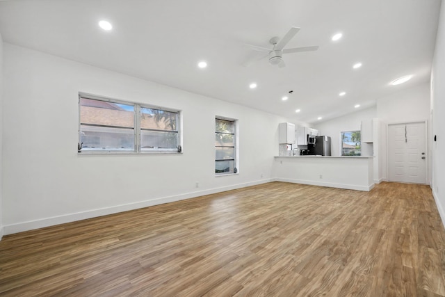 unfurnished living room with ceiling fan, vaulted ceiling, and light hardwood / wood-style flooring