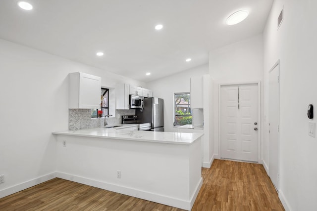 kitchen featuring appliances with stainless steel finishes, tasteful backsplash, white cabinetry, sink, and kitchen peninsula