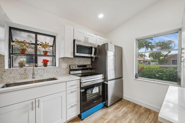 kitchen featuring white cabinetry, sink, decorative backsplash, light hardwood / wood-style floors, and stainless steel appliances