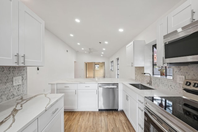 kitchen with white cabinetry, sink, stainless steel appliances, and kitchen peninsula